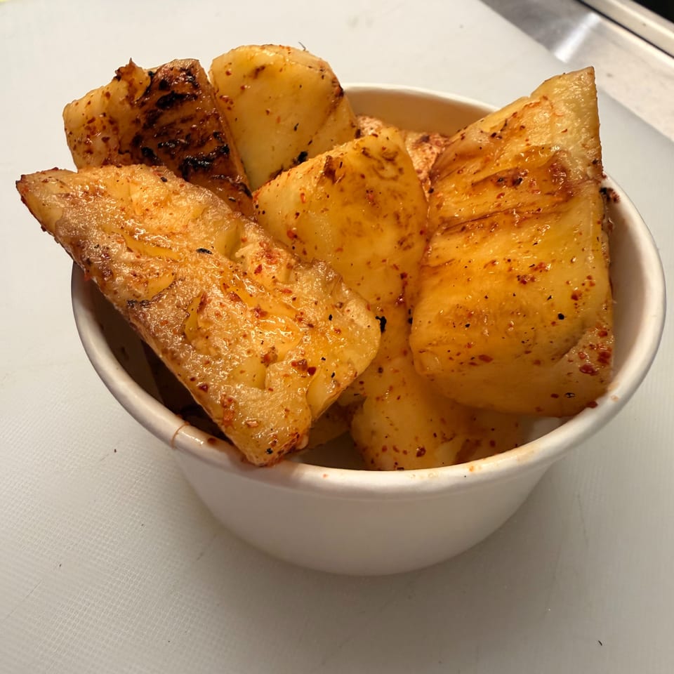 Bowl of roasted potato wedges seasoned with red pepper flakes and herbs on a restaurant table.